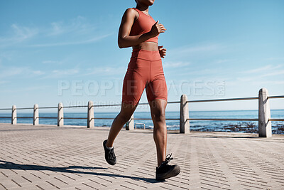Buy stock photo Black woman, legs or running by city beach, ocean or sea in healthcare workout, cardiovascular wellness training or marathon exercise. Runner, sports athlete or personal trainer on promenade fitness