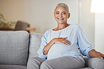 Pregnant woman, smile and relax on sofa in living room for baby health, prenatal care and new mother support. Childcare, baby wellness and pregnancy love, happiness and hands on stomach on couch