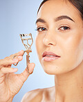 Face, beauty and woman with eyelash curler in studio isolated on a blue background. Portrait, skincare and makeup cosmetics of female model with metal tool or product to curl eyelashes for aesthetics