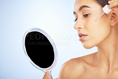 Buy stock photo Face, skincare serum and woman with mirror in studio on a blue background. Beauty, cosmetics and female model with hyaluronic acid, essential oil and dropper product for healthy skin or anti aging.