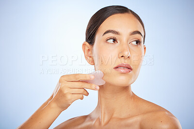 Buy stock photo Woman, face and gua sha product for skincare wellness, beauty or healthy skin glow in blue background studio. Model, facial care and salon spa therapy with stone tool for natural dermatology detox