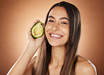 Woman, avocado and face smile, natural skincare or beauty wellness in studio for cosmetics dermatology treatment. Model happiness, facial care and healthy lifestyle with vegetable in brown background