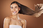 Hair, beauty and skincare with a model woman in studio on a brown background for natural or keratin treatment. Face, haircare and salon with an attractive young female posing to promote a product