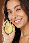 Woman, face and smile portrait with avocado for skincare beauty, natural organic dermatology or cosmetics wellness in brown studio background. Model, detox happiness and luxury facial care nutrition 