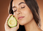 Woman, face and avocado for natural skincare beauty, luxury salon spa detox and closed eyes in brown studio background. Model, facial care glow and organic cosmetics dermatology or nutrition diet