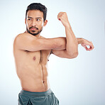 Health, fitness and man stretching arm for flexibility in studio isolated on a blue background. Thinking, sports and young male athlete, warm up and getting ready for training, exercise and workout.