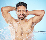 Portrait, water and shower with a man model in studio on a blue background for hygiene or hydration. Face, beauty and skincare with a handsome young male wet from a water splash in the bathroom
