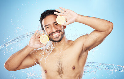 Buy stock photo Portrait, water and lemon with a man model in studio on a blue background for natural hydration or hygiene. Face, fruit and beauty with a handsome young male wet from a water splash in the bathroom