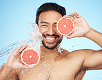 Face, water and grapefruit with a man model in studio on a blue background for hygiene or natural hydration. Skincare, beauty or fruit with a handsome young male wet from a water splash in the shower
