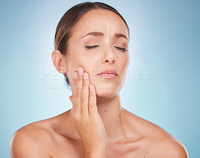 Buy stock photo Toothache, dental hygiene and oral care with a model woman holding her face in pain on a blue background. Dentist, cavity and mouth with an attractive young female touching her cheek in studio