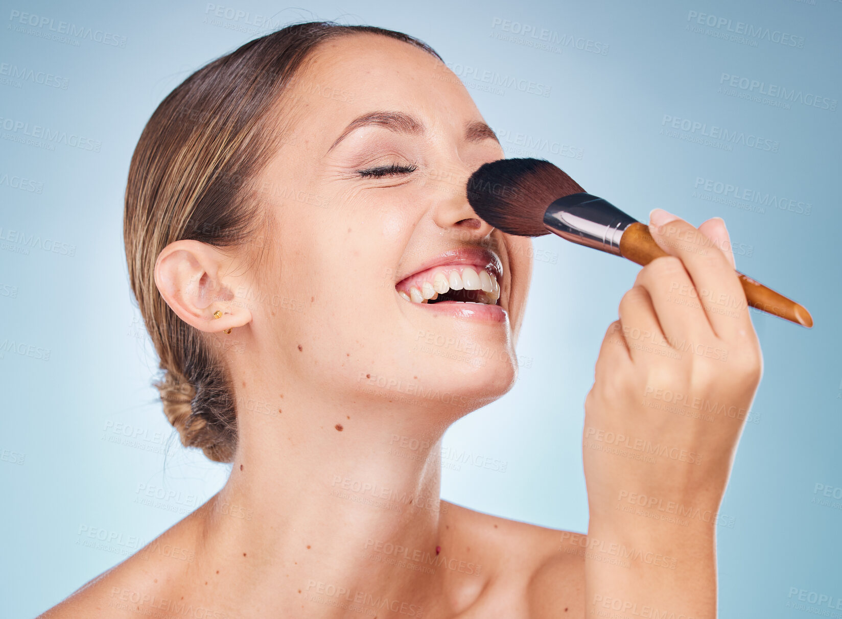 Buy stock photo Woman, face and smile with makeup brush for skincare beauty, dermatology wellness and cosmetics treatment in blue background. Model happiness, facial care and luxury product application in studio