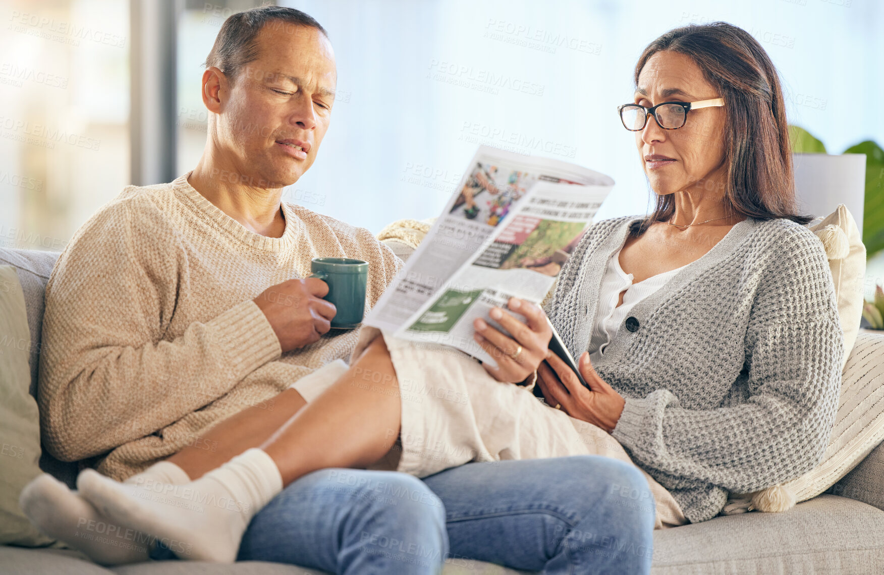 Buy stock photo Senior couple, newspaper and relax talking on sofa reading, morning conversation or quality time bonding together in living room. Elderly man, woman and news discussion, coffee and retirement peace