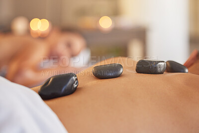 Buy stock photo Stone, man or woman at a spa for a massage, relaxing self care or luxury physical therapy healing for back pain. Hot stone massage, zoom or customer on a bed for healthy natural holistic treatment 