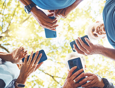 Buy stock photo Fitness, group with smartphone in hands and running in park, technology low angle and check exercise mobile app. Elderly runner team outdoor with health, phone for cardio and sports motivation.