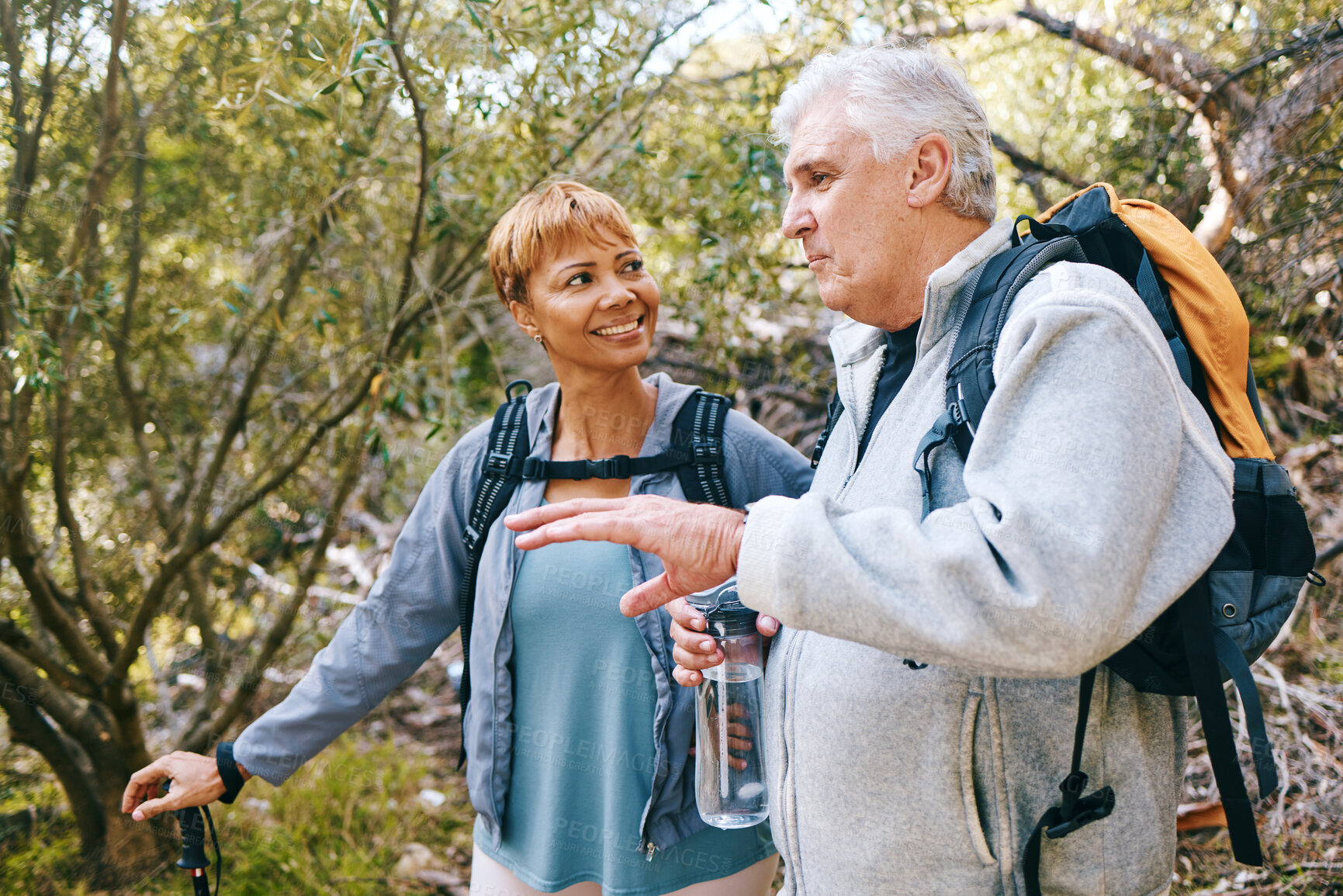 Buy stock photo Relax, senior or couple of friends hiking, walking or trekking for freedom, exercise or fitness in nature forest. Interracial, travel or happy woman enjoys bonding time with healthy elderly partner