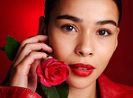 Portrait, beauty and red rose with a model woman holding a flower in studio on a wall background for valentines day. Face, romance and love with an attractive young female posing to promote dating