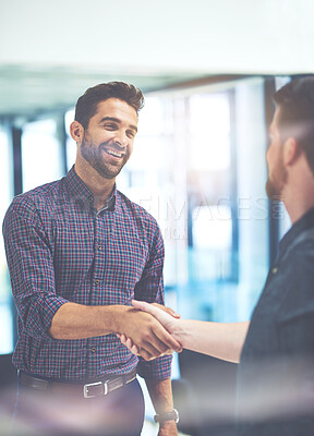 Buy stock photo Shot of two young businessmen shaking hands in an office