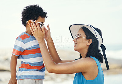 Buy stock photo Shot of a mother applying sunscreen to her son at the beach