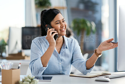 Buy stock photo Shot of a young businesswoman talking on a cellphone while working on a computer in an office