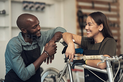 Buy stock photo Shot of two young business owners standing together in their bicycle shop during the day