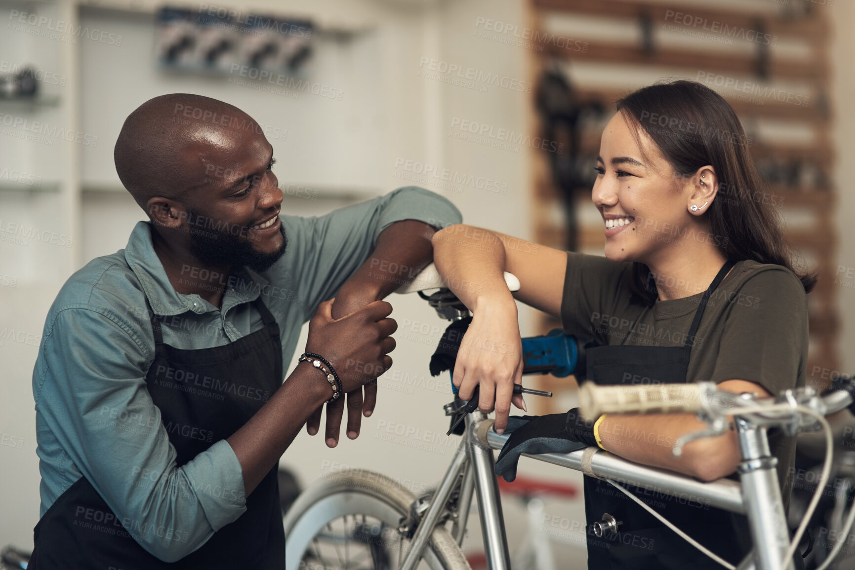 Buy stock photo Shot of two young business owners standing together in their bicycle shop during the day