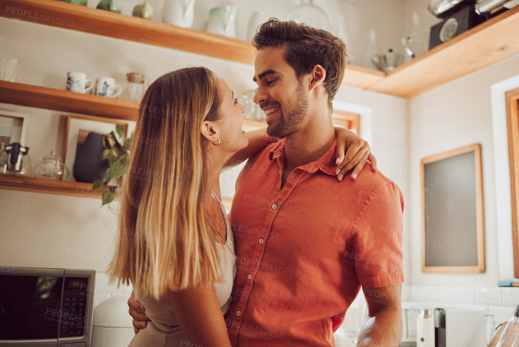Buy stock photo Romance, happy and love couple hugging, smile and bonding in kitchen. Romantic boyfriend and girlfriend embracing, enjoying their relationship and being carefree together.