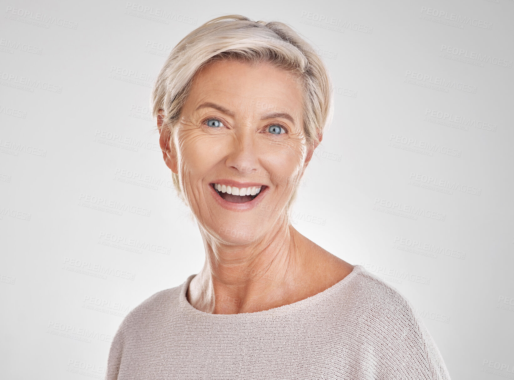 Buy stock photo Portrait of one happy caucasian mature woman isolated against a grey copyspace background. Confident smiling senior woman looking cheerful while showing her natural looking teeth in a studio