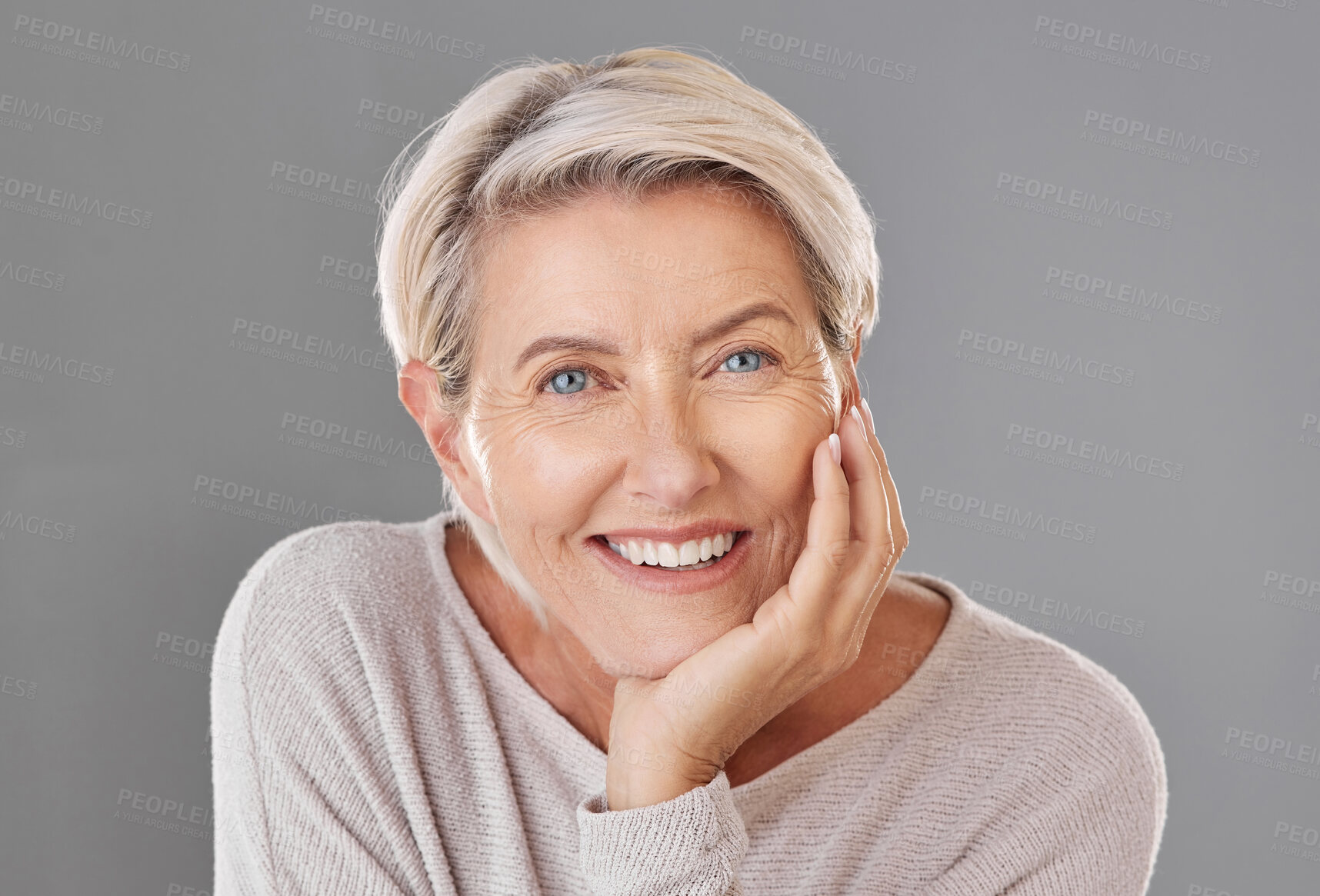 Buy stock photo Portrait of one happy caucasian mature woman isolated against a grey copyspace background. Confident smiling senior woman looking cheerful while showing her natural looking teeth in a studio