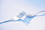 Dinner, shadow and forks on a table for partnership, teamwork and collaboration on a blue studio background. Creative, design and kitchen utensils with reflection of solidarity and team work