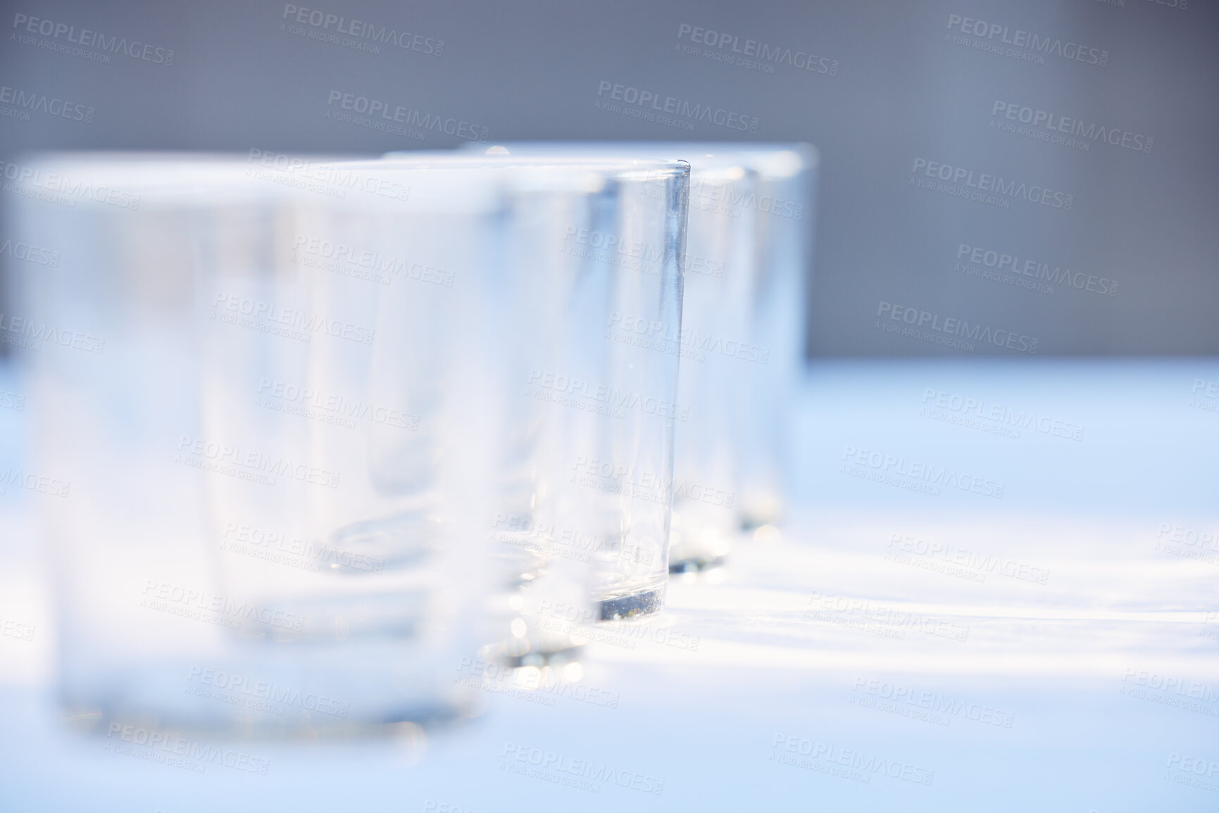 Buy stock photo Glass, crockery and mockup with a row of drinking glasses on a table in a studio or restaurant for fine dining. Space, glassware and drinks with a group of cups in a line for a beverage while dining