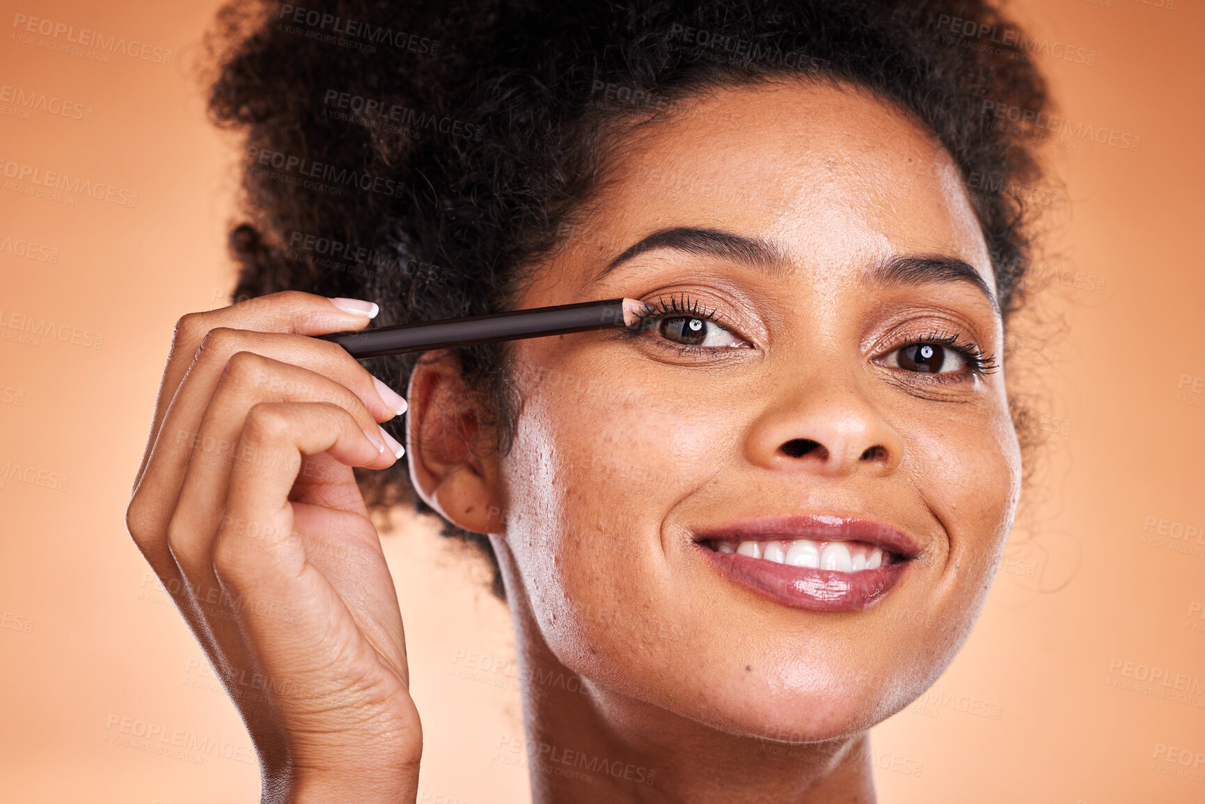 Buy stock photo Beauty, skincare and makeup with black woman using eyeliner on eye for facial cosmetics product on a orange studio background. Face portrait of aesthetic model with smile and happiness for self care