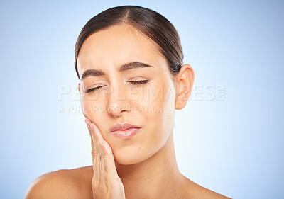 Buy stock photo Toothache, pain and cavity with a model woman holding her mouth in studio on a blue background for oral care. Dental hygiene, plaque and face with an attractive young female rubbing her sore cheek