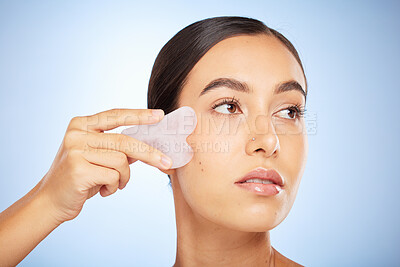 Buy stock photo Skincare woman, crystal glow and gua sha for wellness, beauty and cosmetic health by blue background. Model, skin and self care with rose quartz, cosmetics and cleaning face for self love by backdrop