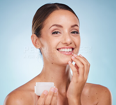Buy stock photo Portrait, skincare or lotion with a model woman holding a container in studio on blue background to promote beauty. Face, wellness or luxury and an attractive young female with cream to apply on skin