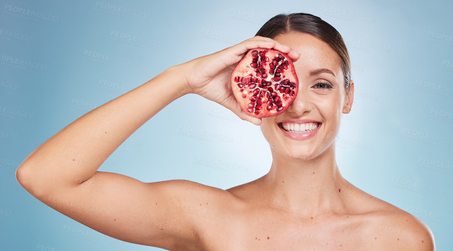 Buy stock photo Face portrait, skincare and woman with pomegranate in studio on a blue background. Organic cosmetics, beauty and female model with product, fruit or food for vitamin c, nutrition and healthy diet.