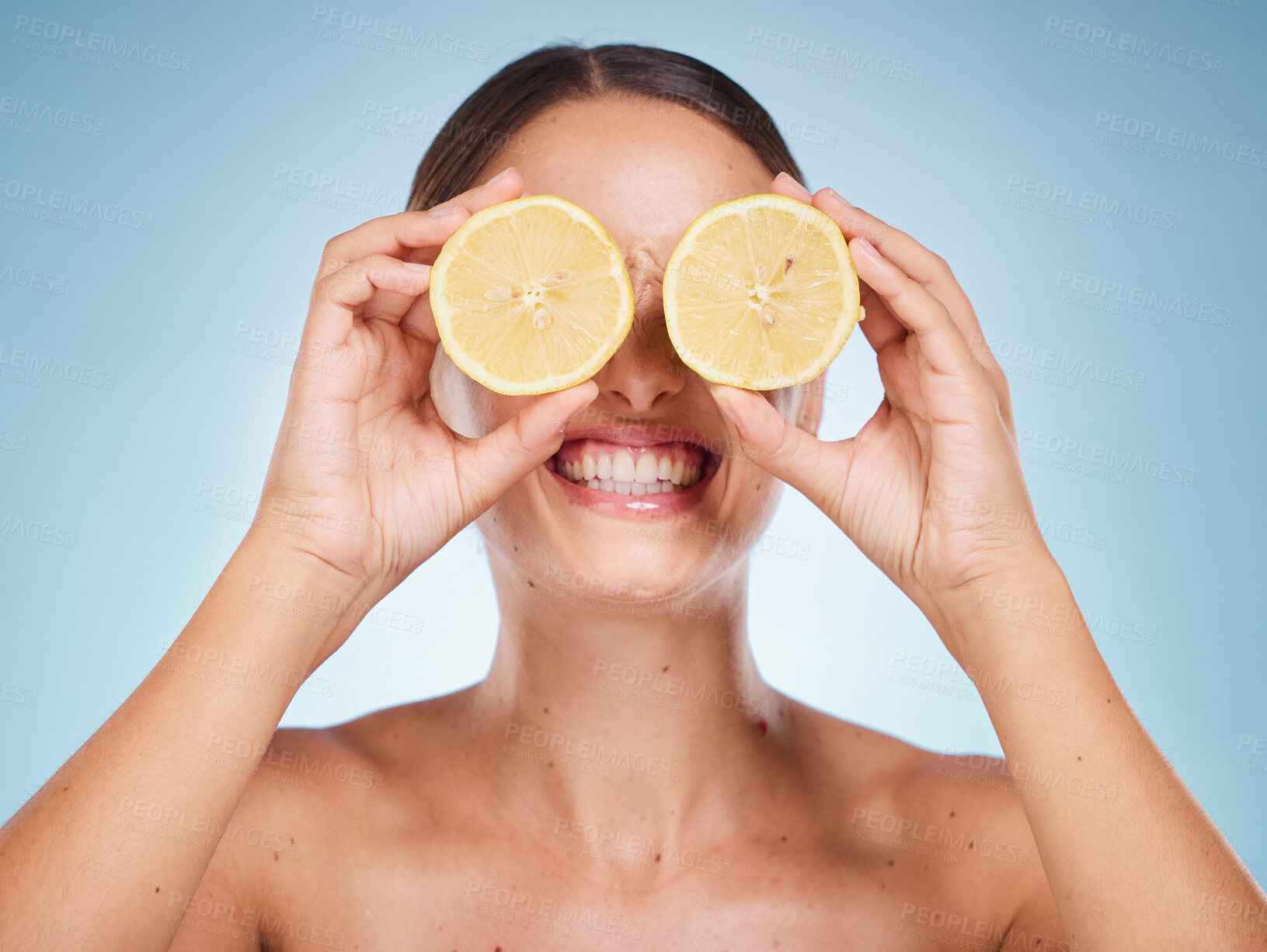 Buy stock photo Beauty, lemon and skincare with a model woman in studio on a blue background for natural treatment. Wellness, luxury and fruit with an attractive young female posing to promote health or skin care