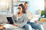 Tablet, newspaper and couple relax on sofa, bonding and streaming video at home. Technology, love and mature man reading news and woman with touchscreen on social media or internet browsing in house.
