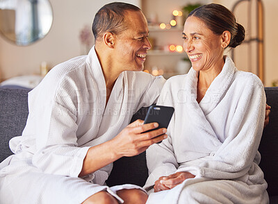 Buy stock photo Senior couple, phone and relax spa wellness on sofa, beauty center and luxury body care or streaming video online. Happiness, woman and man smile together for love with smartphone and therapy gown