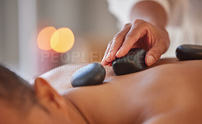 Buy stock photo Spa, man and stone massage to relax, wellness and health for body care, peace or holistic care. Male, gentleman or lying on table at luxury resort, zen or therapy for skincare with rocks