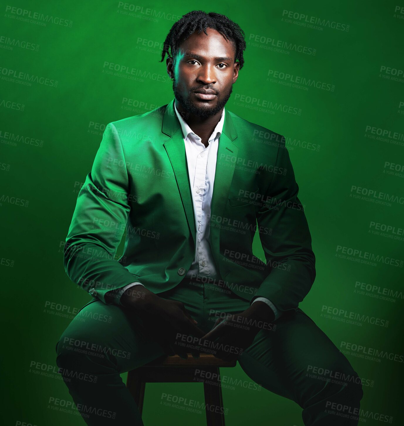 Buy stock photo Fashion, formal and portrait of a black man in a suit sitting on a chair in studio with a luxury outfit. Elegant, stylish and African male model with fashionable clothes isolated by green background.