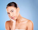 Face portrait, skincare and beauty of woman in studio on a blue background. Hands, natural cosmetics and makeup of young female model with healthy, smooth and glowing skin after facial treatment.