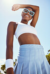 Fashion, sports and black woman posing outdoor with cool, edgy and stylish outfit and sunglasses. Happy, smile and African female model with edgy, funky and fashionable style standing on tennis court