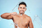 Face, water splash and man with toothbrush for cleaning in studio on blue background. Dental veneers, hygiene and portrait of happy male model brushing teeth for oral wellness, health or fresh breath