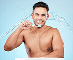 Teeth, dental care and water splash, man with toothbrush and toothpaste on blue background with smile on face. Morning routine, healthcare and fresh studio portrait of model in India brushing teeth.
