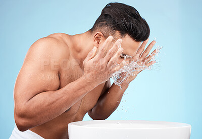 Buy stock photo Clean, grooming and man washing face with water for skincare, morning hygiene and care of body on a blue studio background. Beauty, wellness and model with a facial water splash for cleaning