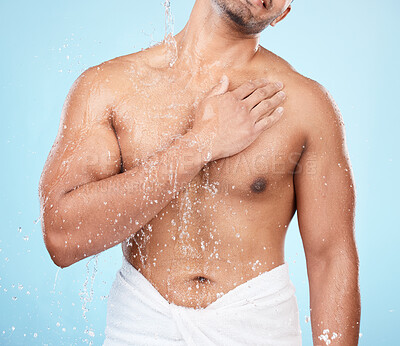 Buy stock photo Body, water and shower with a man model standing in studio on a blue background for hygiene or hydration. Splash, health and wellness with a male wearing a towel in the bathroom after bathing
