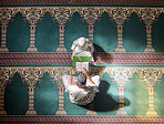 Muslim pray, child or man in praying with Quran for peace, mindfulness or support from Allah in holy mosque. Top view, Islamic kid or person studying or praying to help worship God on Ramadan Kareem