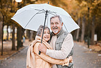 Winter, hug and senior couple in a park, retirement date and walking in Canada with an umbrella. Nature affection, smile and portrait of an elderly man and woman on a walk for happiness and love