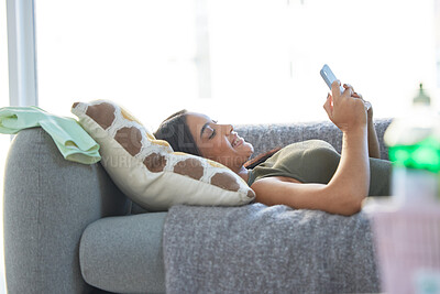 Buy stock photo Indian woman, phone and relax happy on sofa for social media, online communication and streaming video on web mobile app. Female, calm peace and relaxation or happiness watching meme on smartphone 