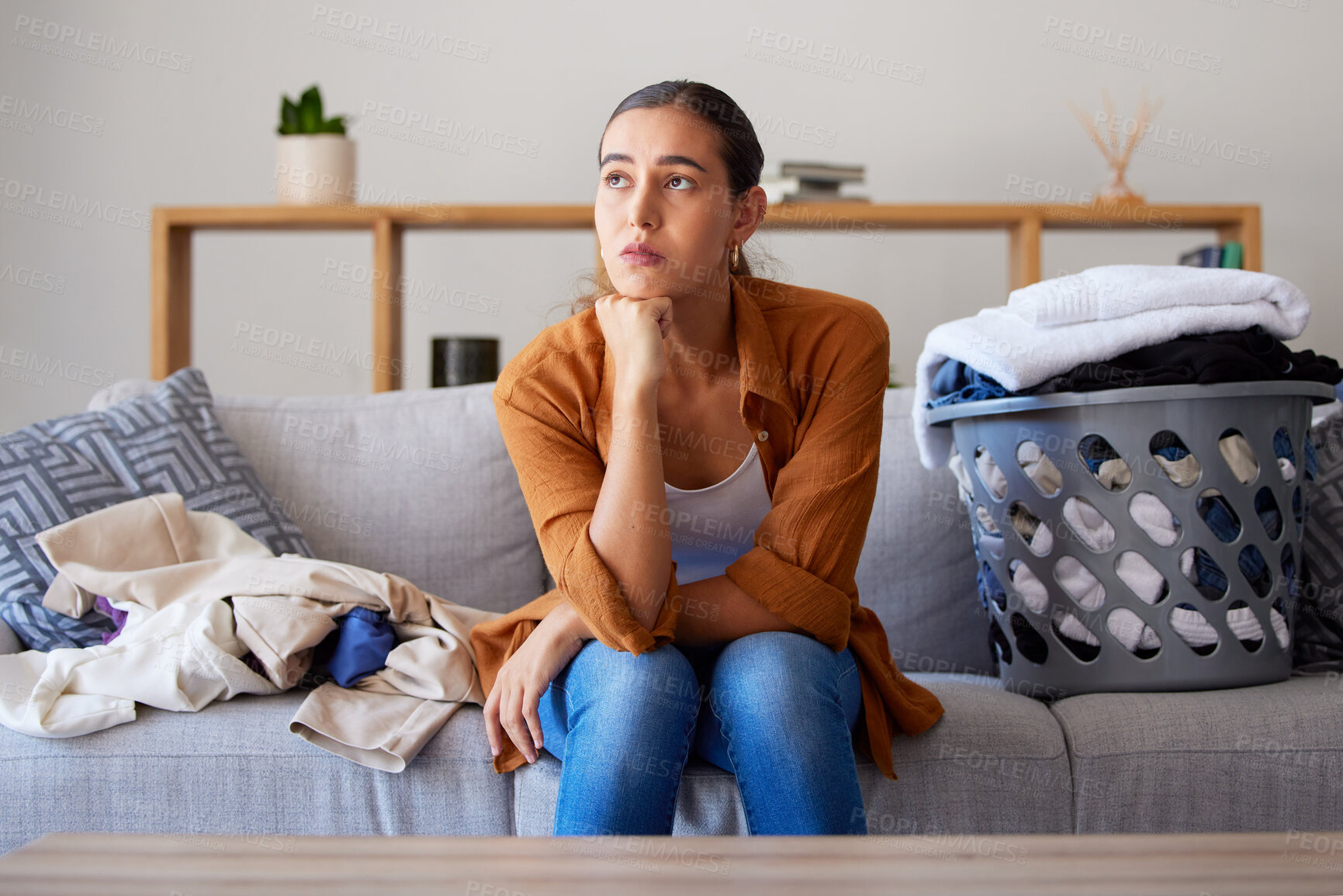 Buy stock photo Laundry, bored and break with a woman cleaner sitting on a sofa in her living room at home for spring cleaning. Depression, cleaning and laundry basket with a female housekeeper resting on a couch